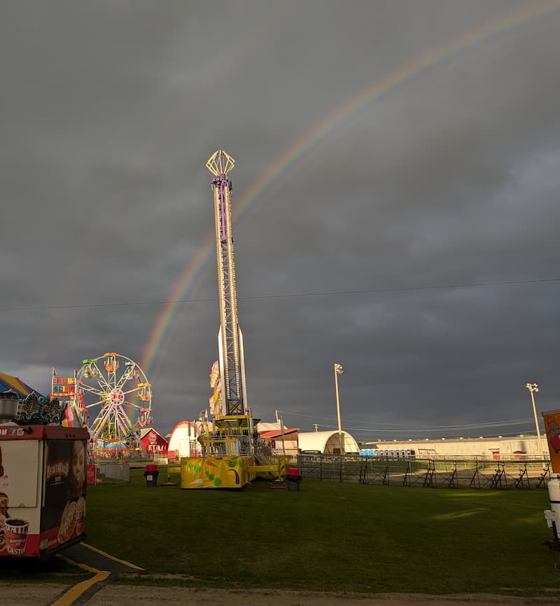A rainbow over the Beachburg midway, the drop tower and Ferris wheel under a dark sky