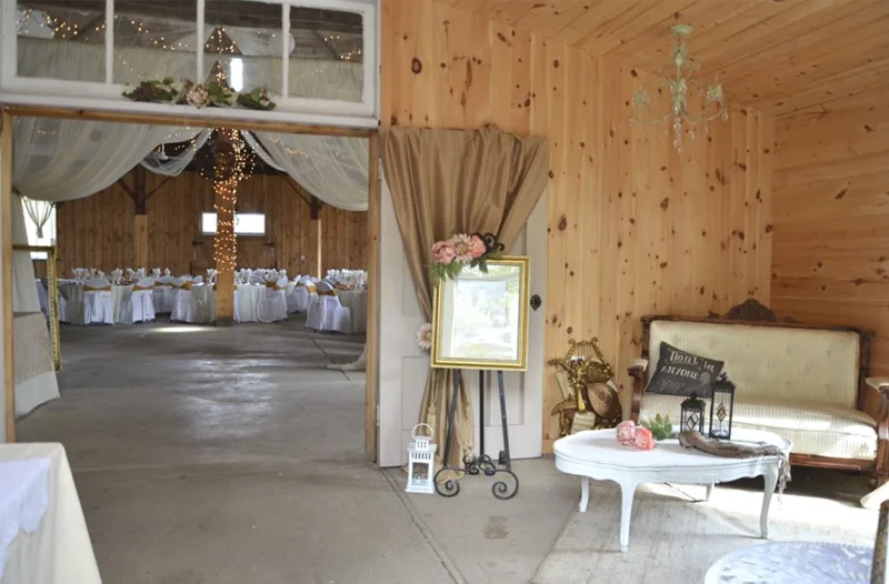 The pine-panelled entrance room of Heritage Hall dressed for a wedding, with a settee and welcome sign, looking through to the tables in the main hall